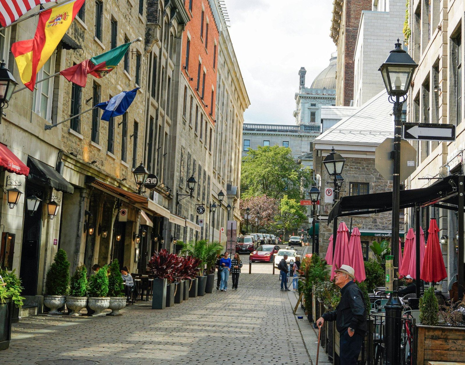 Une rue pavée du Vieux-Montréal bordée d’immeubles de pierre, de lampadaires et de terrasses de cafés