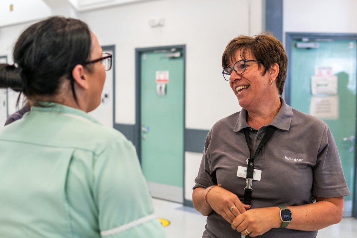 Deux membres du personnel d’un hôpital échangent un sourire dans un corridor lumineux