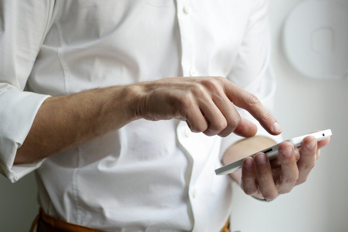 Une personne en chemise blanche utilise un téléphone intelligent
